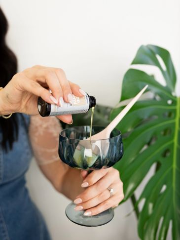 Pouring liquid into a glass with a leaf background.
