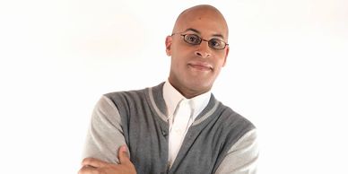 Confident man in glasses and cardigan posing with arms crossed.