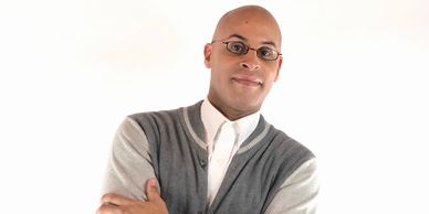 Confident man in glasses and cardigan posing with arms crossed.