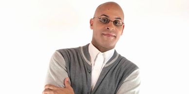 Confident man in glasses and cardigan posing with arms crossed.