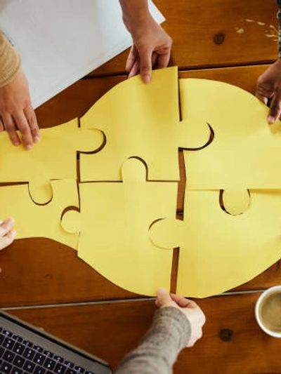 Team putting the pieces together of a lightbulb puzzle with Fractional CMO Services