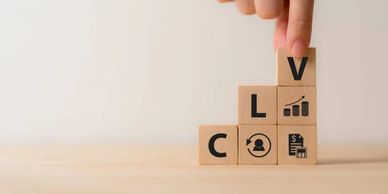 Hand building a step-by-step block with the letters CLV and diagrams indicating growth