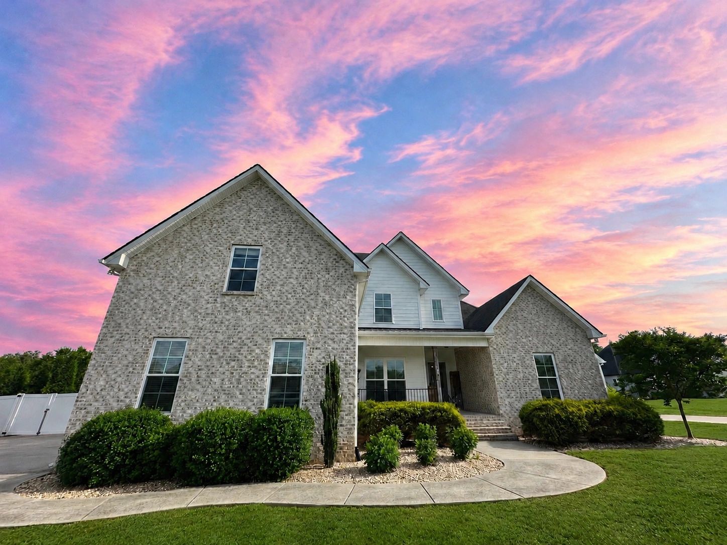 Modern brick house under a vibrant pink and blue sunset sky.