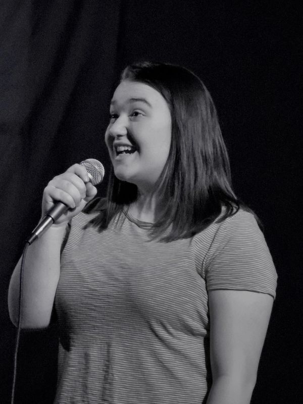 Young woman happily singing with a microphone.