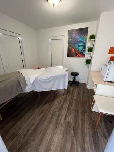 Cozy massage therapy room with a treatment table and calming artwork.