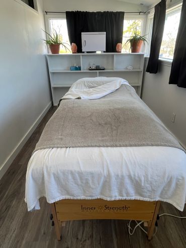 Cozy massage room with a neatly made table and natural light.