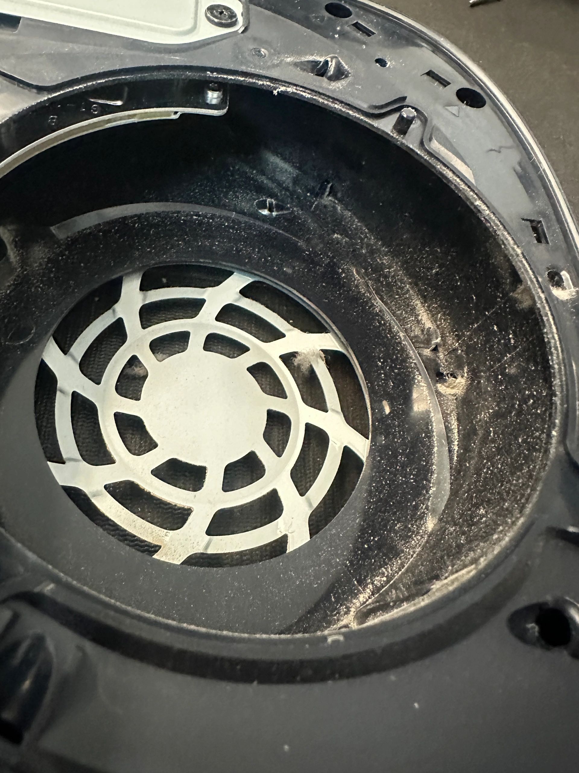 Dusty black plastic circular component with white grille.
