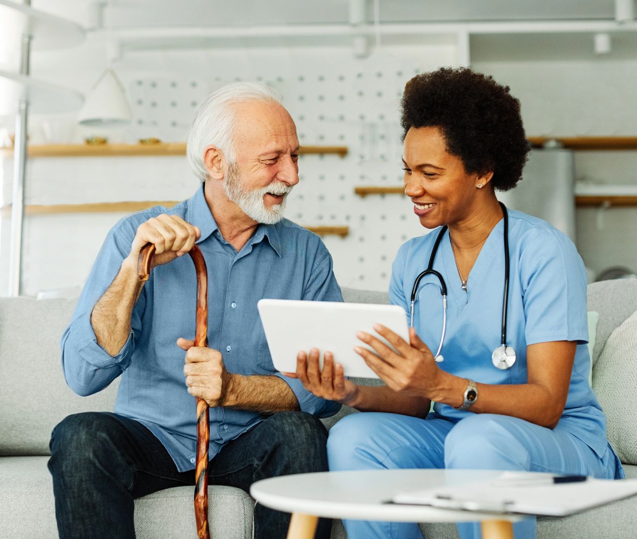 A senior man and a nurse looking at a tablet.