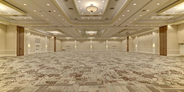 Spacious empty ballroom with decorative carpet and elegant ceiling lights.