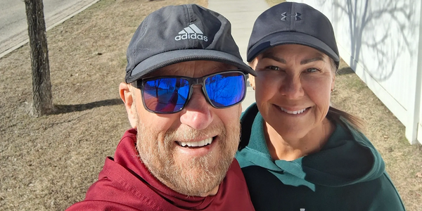 A happy couple posing for a selfie outdoors on a sunny day.