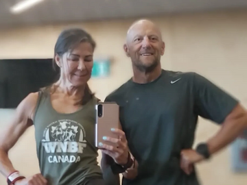Two fit individuals posing in gym attire, taking a mirror selfie.