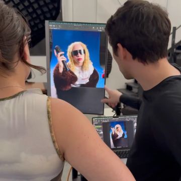 Two people reviewing a photo of a woman in sunglasses on a large monitor.