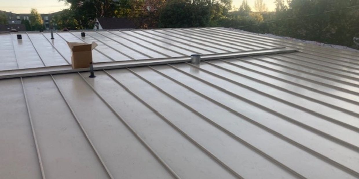 A metal rooftop with a small cardboard box and ventilation pipes.