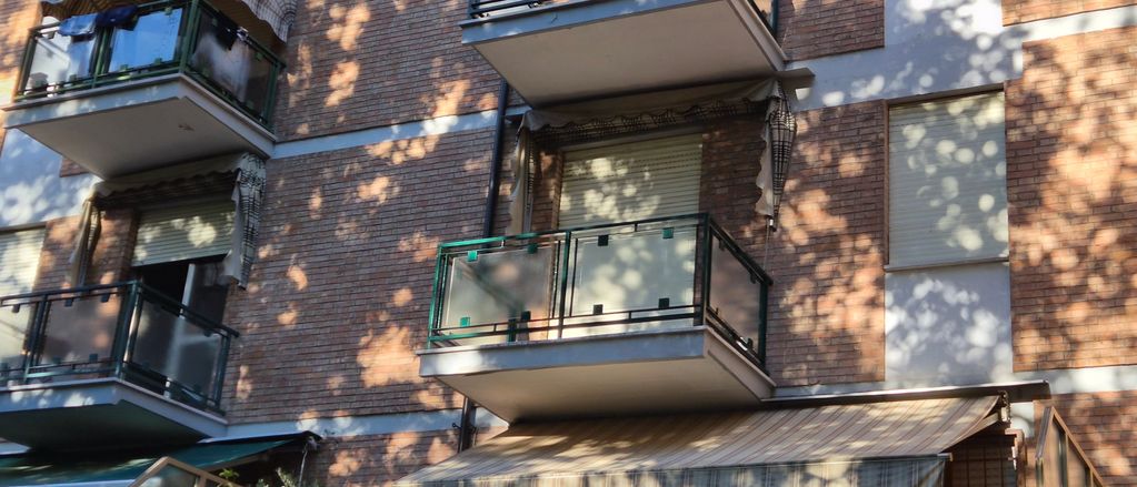 Balconi con ringhiere in vetro su edificio in mattoni.