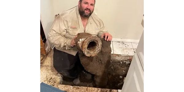 Florida certified plumbing contractor holding old deteriorating cast iron sewer pipe 