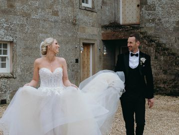 Bride and groom smiling at each other outdoors.