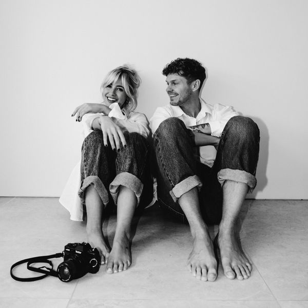 Couple sitting barefoot on the floor, smiling.