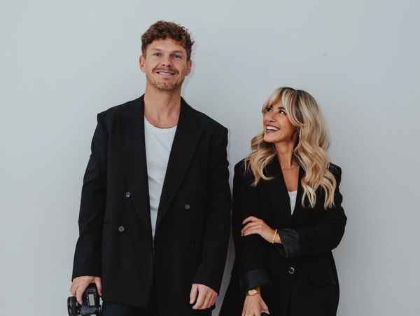 Smiling man and woman in black blazers.