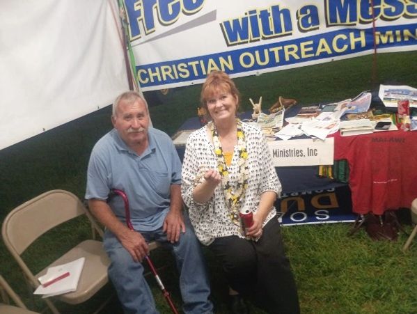 Man and woman sitting at a Christian outreach booth.