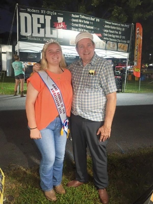 Two people smiling at an outdoor event at night.