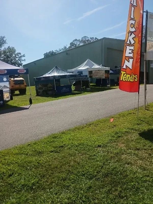 Outdoor food stalls with tents under a clear blue sky.