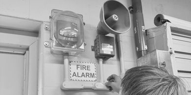 Protection Associates technician inspecting a fire alarm system in a commercial building hallway