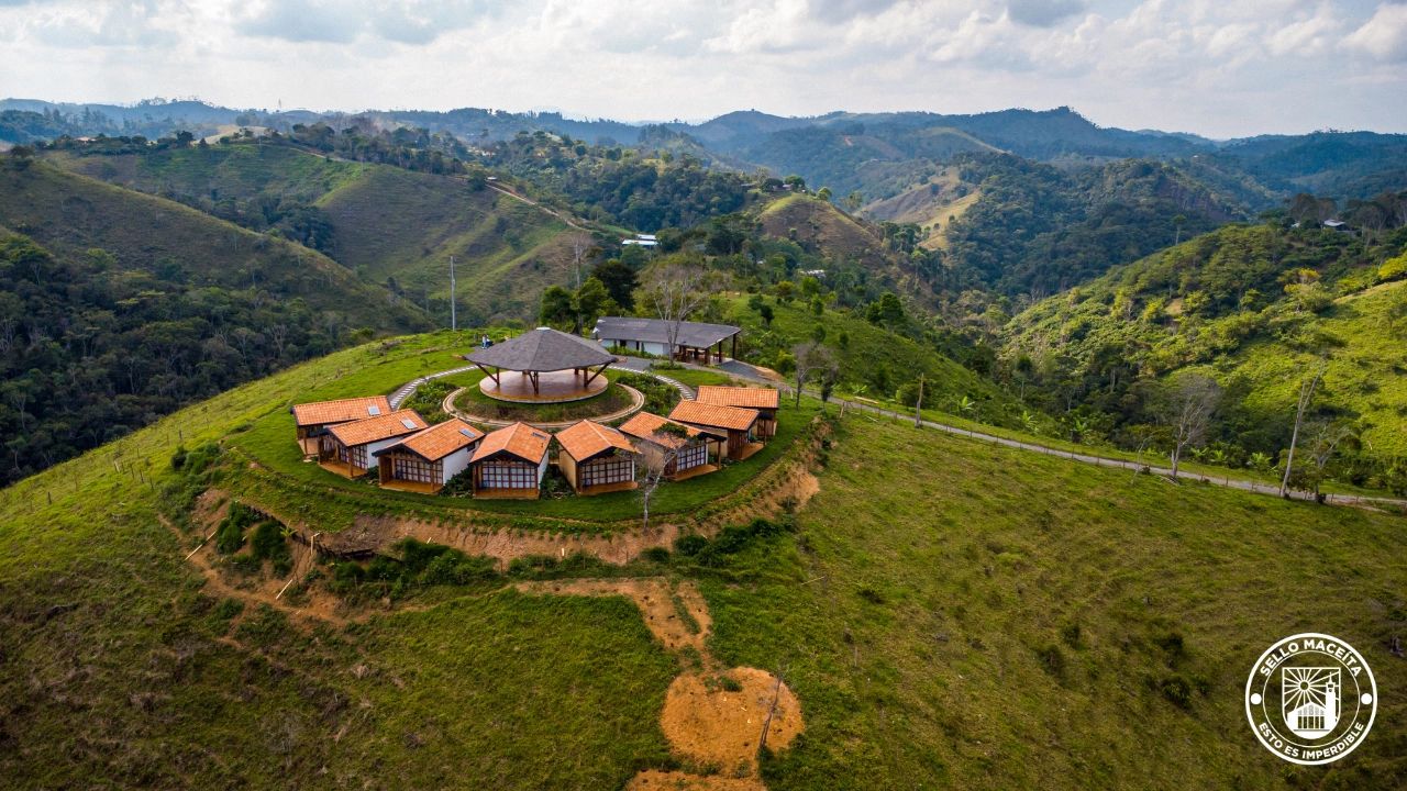 Scenic hilltop retreat with circular wooden cottages surrounded by lush green mountains.