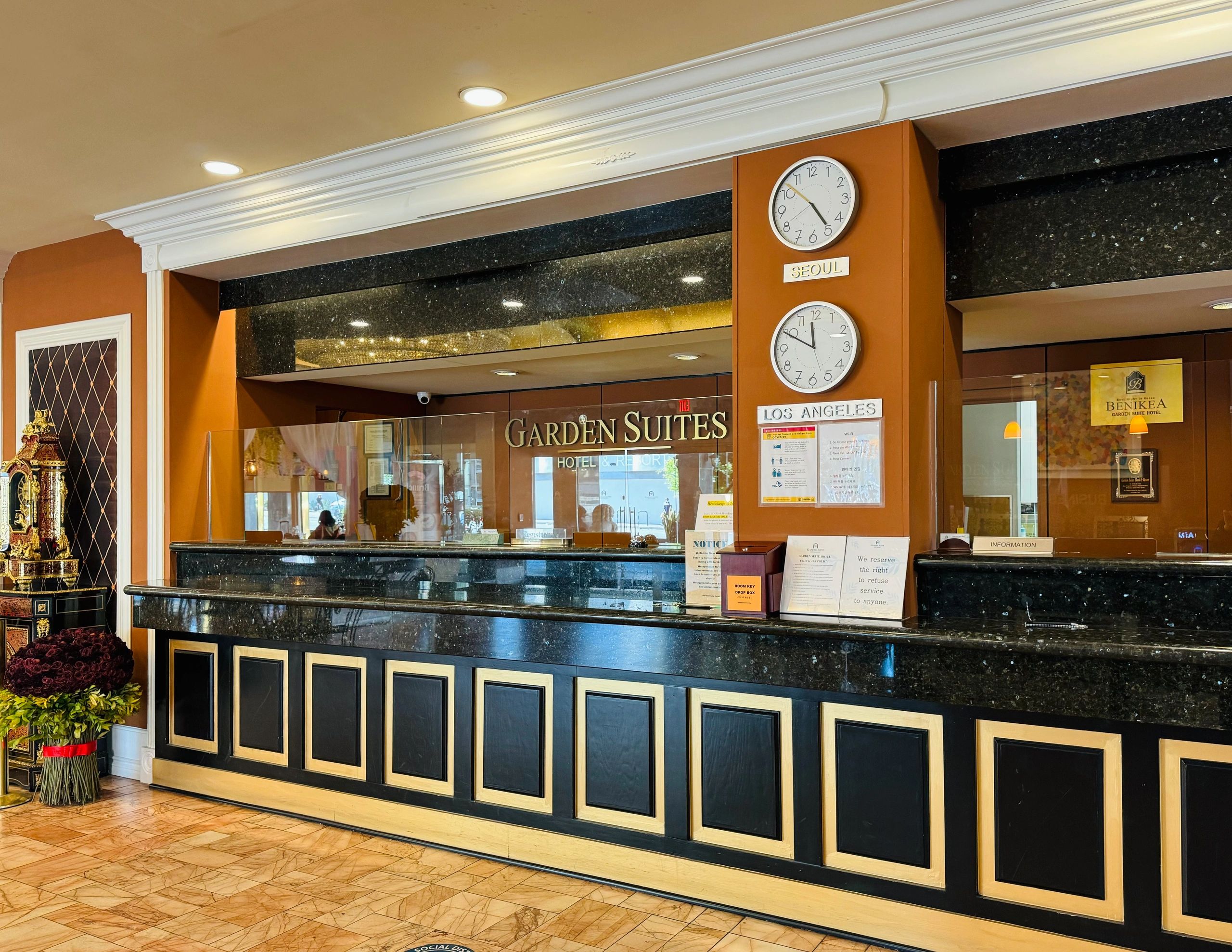 A hotel lobby with a black marble reception desk and a clock on the wall.