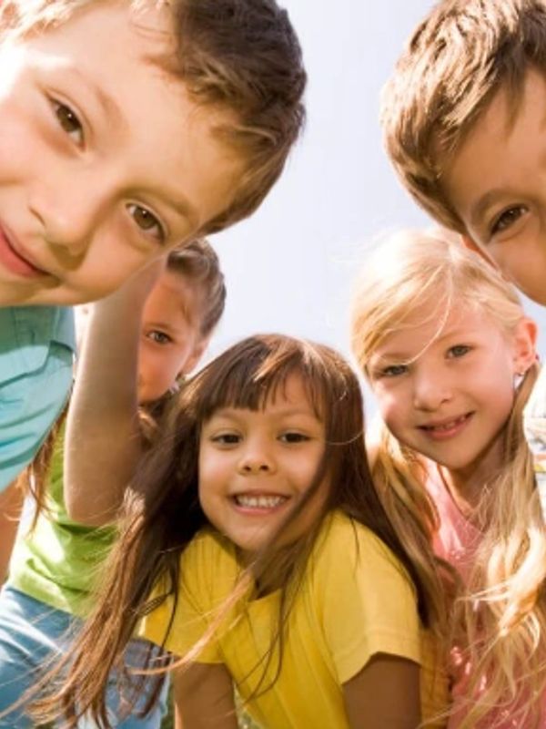 Group of smiling kids posing together outdoors.