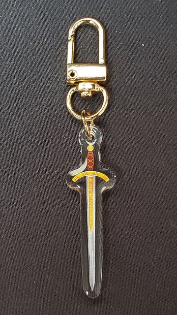 Gold keychain with sword-shaped charm on a black background.