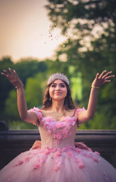 Quinceañera wearing a colorful gown throwing confetti.