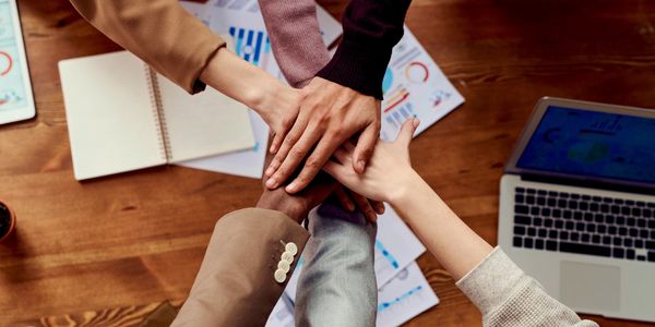 6 hands reaching together over a table.