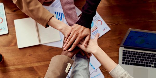 6 hands reaching together over a table.