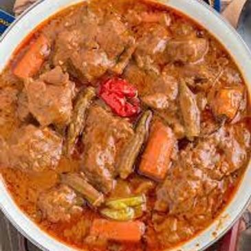 A bowl of spicy beef stew with carrots and peppers.