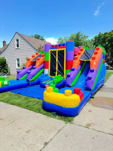 Colorful inflatable bounce house with slides in a sunny backyard.