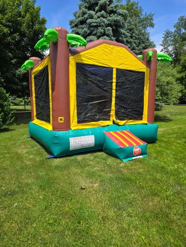 Colorful inflatable bounce house with palm tree decorations on a sunny day.