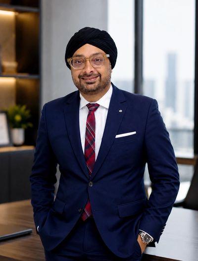Professional man in a suit and turban smiling indoors.