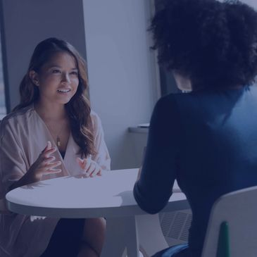 Two racially diverse women chat at a table. | Photo by Christina @ wocintechchat.com on Unsplash