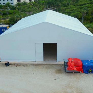 Large white tent with an open entrance on a dirt ground.