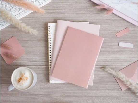 Notebooks and a coffee cup on a wooden table.