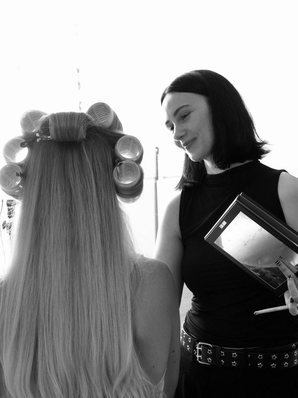 Woman with hair rollers and hairstylist holding a palette.