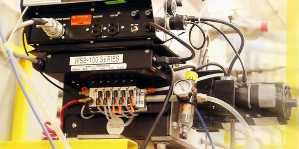 Close-up of industrial control system with wiring, pneumatic lines, and pressure gauge.