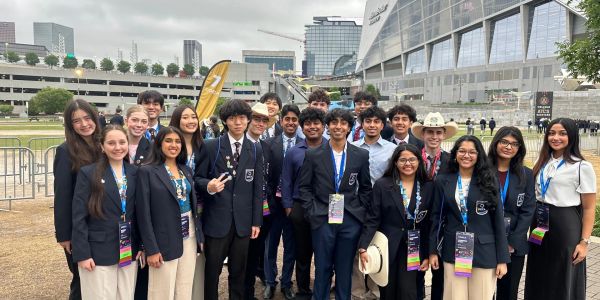 Group of young professionals posing together outdoors in business attire.