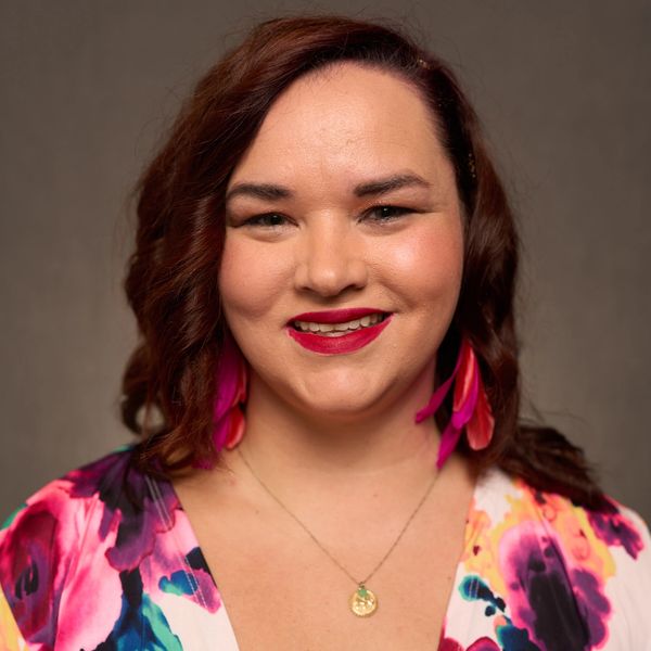 Smiling woman with curly hair and colorful outfit.