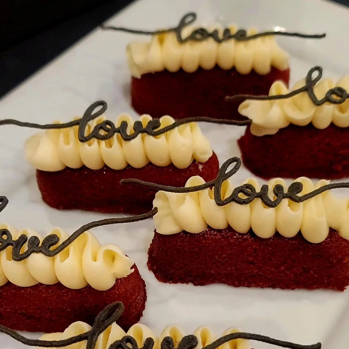 Stamme Velvet topped with a ribbon of cream cheese frosting, garnished with a "Love" tuille.