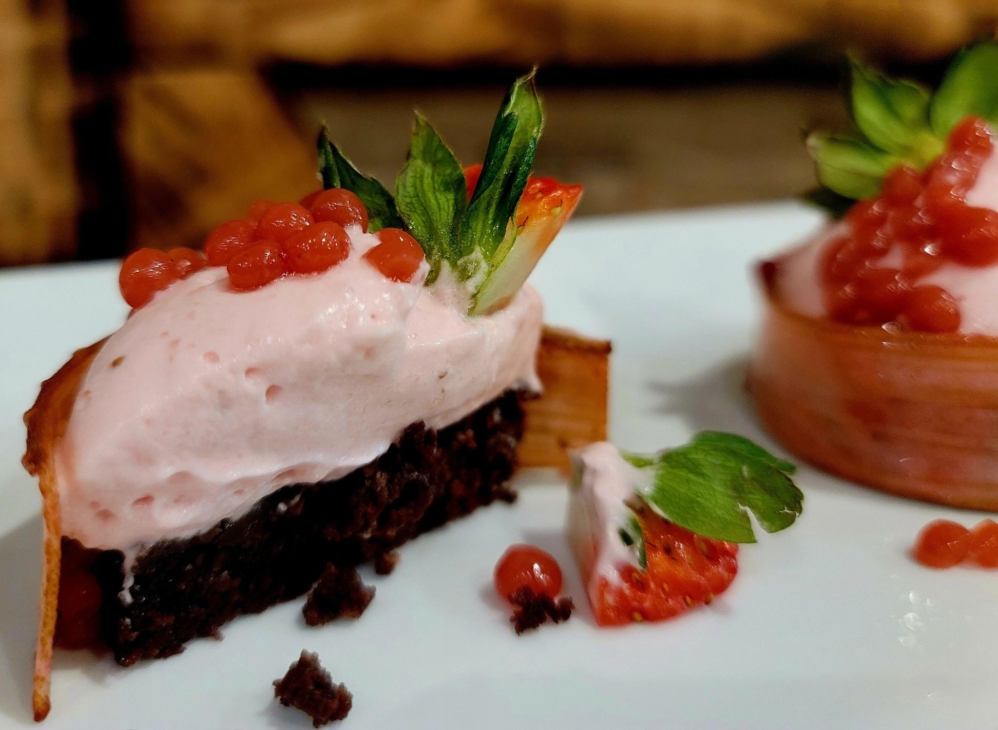 Strawberry Rhubarb Mousse Cakelette topped strawberry pearls and garnished with a strawberry cap.
