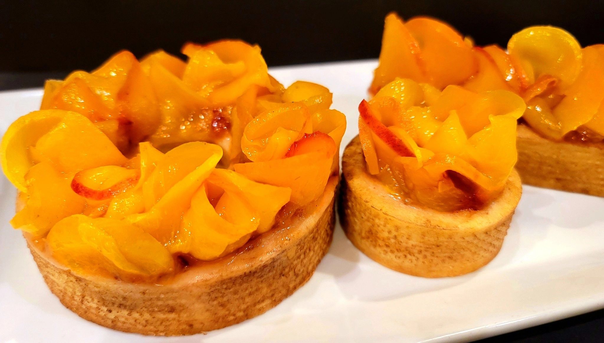 Peach Frangipane Cake in a shortbread tart, topped with a fresh peach compote and garnished with rib