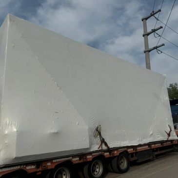Large industrial cargo securely protected with on-site seaworthy shrink wrapping, 