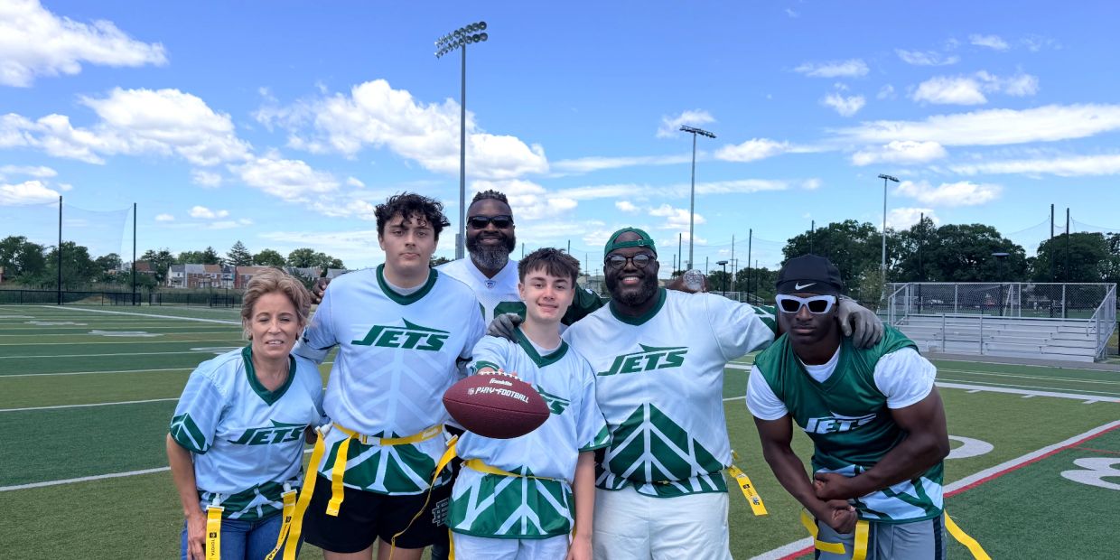 Group of six people in Jets jerseys posing on a football field.