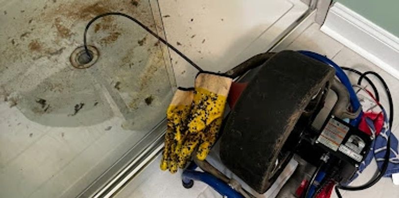 Plumbers snake unclogging shower drain